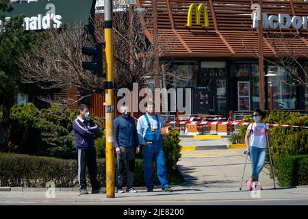 Woman wearing protective face mask standing in front of closed for normal business McDonald's fast food restaurant during the Covid 19 pandemic 2020 Stock Photo