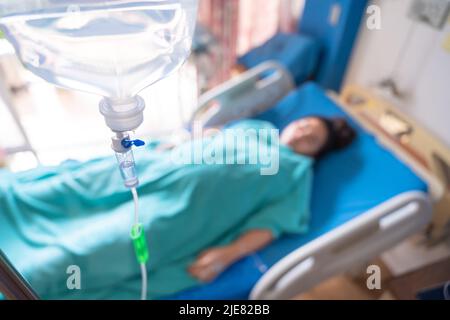 Asian Pregnant Woman patient is on drip receiving a saline solution on bed VIP room at hospital. Medical Concept. Stock Photo