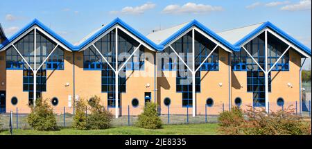 Commercial real estate units repetitive gable end of industrial unit façade repeating architectural triangle features & bullseye windows England UK Stock Photo