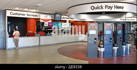 Argos catalogue store interior view of person at Customer Services counter with collection point staff nearby and Quick Pay tills in London England UK Stock Photo