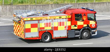 Side back view high visibility markings Essex Fire & Rescue Service fire brigade engine blue light emergency shout driving English UK motorway road Stock Photo