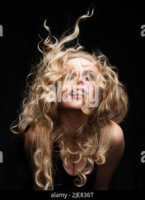 Portrait of nice attractive pretty cute charming woman with blonde hair in motion on black background Stock Photo