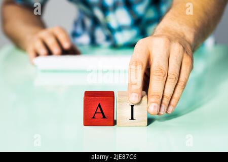 Man arranging blocks with the inscription AI, Concept of the influence of modern technology and the progress of work on the development of artificial Stock Photo