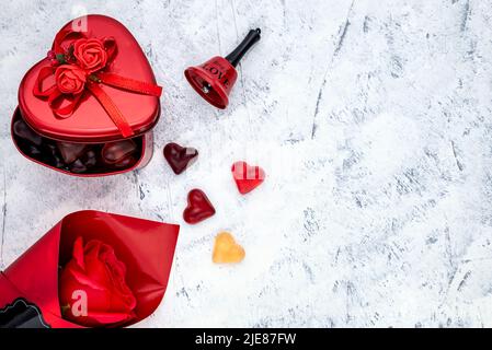 Heart-shaped gummy candies with a metal gift box, red rose and bell for Valentine's Day or Women's Day. Top view. Stock Photo
