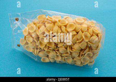 Orecchiette pasta in transparent sealed package for sale on blue background, Italian pasta from Puglia made with durum wheat flour and water, typical Stock Photo