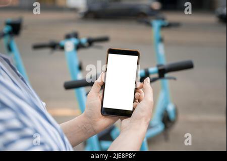 woman holds in her hands a smartphone to pull down the screen. pays for renting an electric scooter Stock Photo