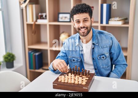 Young arab man playing chess sitting on table at home Stock Photo