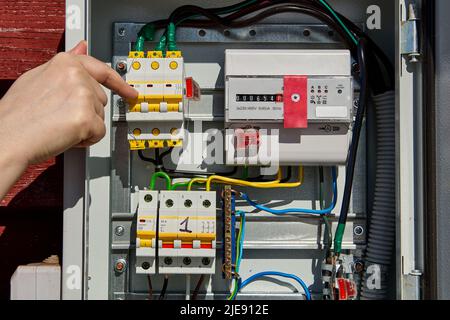 Switching circuit breaker in switchboard with electricity meter. Stock Photo