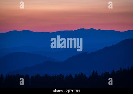 Sky above a mountain landscape at twilight, covered with colorful clouds. Stock Photo