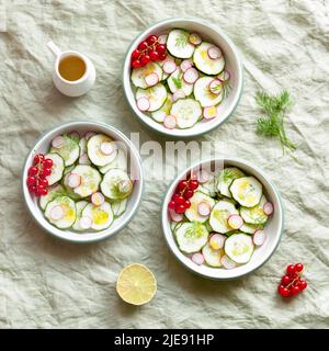 Radish and cucumber salad served in round bowls, decorated with red currants Stock Photo