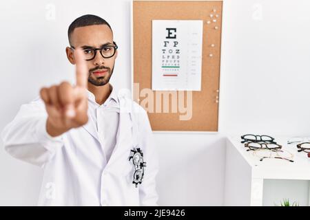 African american optician man standing by eyesight test pointing with finger up and angry expression, showing no gesture Stock Photo