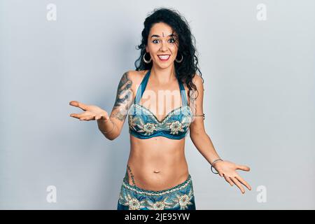 Young woman wearing bindi and traditional belly dance clothes smiling cheerful with open arms as friendly welcome, positive and confident greetings Stock Photo