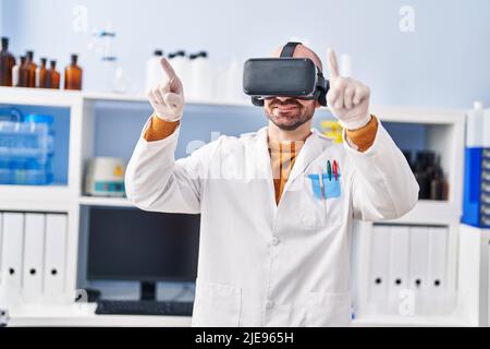 Young man scientist using virtual reality goggles at laboratory Stock Photo