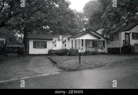 1980, historical, exterior view of a wooden-framed bungalow, with large covered front porch located in a woody suburb of Atlanta, Georgia, USA, with mailbox outside on front lawn. Stock Photo