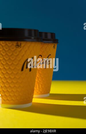 Ukraine, Kyiv - February 17, 2021: Yellow glass of coffee from McDonald's. Paper glass drink McCafe. offee cup on table with shadows. Menu in fastfood restaurant. Stock Photo