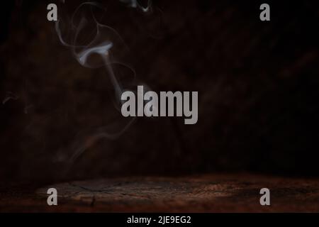 Empty wooden table with smoke float up on dark background Stock Photo