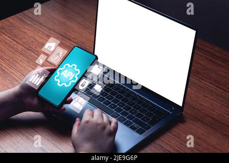 API concept with smartphone interface and blank laptop screen for mockup. Application Programming Interface. Software Development. Stock Photo