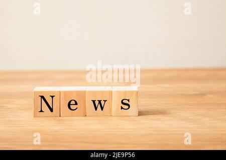 News characters. news. What's New. Written on four wooden blocks placed on a wooden table. Black letters. Stock Photo