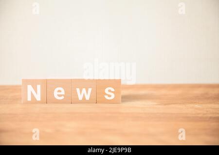 News characters. news. What's New. Written on four wooden blocks placed on a wooden table. White letters. Stock Photo