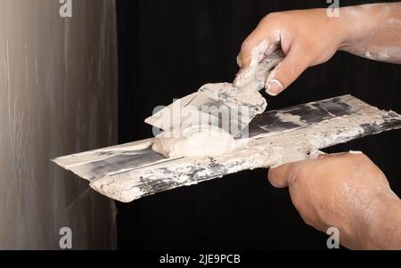 master spreads putty on a spatula, wall repair. Stock Photo