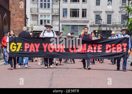 London, UK. 26th June 2022.  Extinction Rebellion activists march past St James's Palace. The action was part of the day’s protest and march demanding that the G7 cancels the debt of the countries in the Global South, which is forcing the nations to extract fossil fuels to pay off the debts. Credit: Vuk Valcic/Alamy Live News