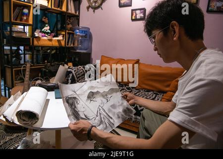 (220626) -- LIJIANG, June 26, 2022 (Xinhua) -- Liu Zhicheng draws up the draft of a wall painting at home in Yongsheng County, Lijiang City, southwest China's Yunnan Province, June 25, 2022. A non-profit 'post-95s' wall painter, hailing from Yongsheng County of Lijiang City, gained popularity both among villagers in his hometown and netizens on social media platforms. The mural artist named Liu Zhicheng has painted more than 20 wall paintings of different themes in many villages of his hometown. His artworks have added color to the villages and attracted many tourists as the short videos Stock Photo