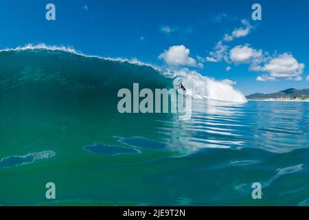 March 27, 2022. Brazil, Florianopolis. Athlete man during surfing. Surfer ride on surfboard in barrel wave. Stock Photo
