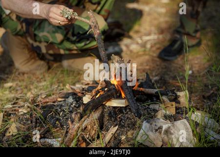 Man is making campfire in the woods. The concept of adventure, travel, tourism, camping, survival and evacuation. Stock Photo