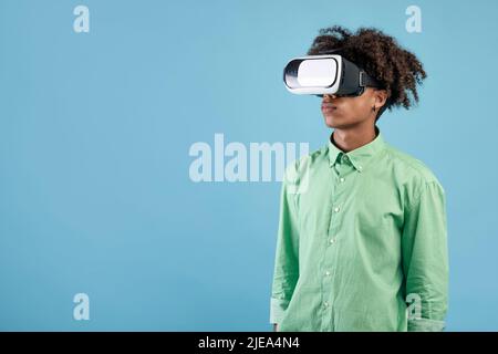 African american teen guy wearing VR headset, using virtual reality for entertainment, exploring cyberspace, free space Stock Photo