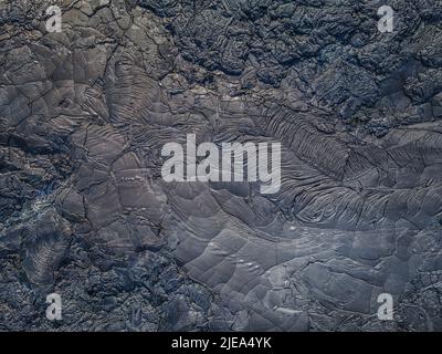 Top view of solidified lava. Dark colored structures from lava flow. Pattern of deferred and broken stones. Different shades of gray. wavy and jagged Stock Photo