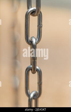 Vertical, partial blurred iron chain on blurred background. Low angle view of steel chains. Stock Photo