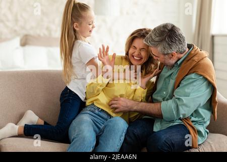 Family Having Fun Tickling And Cuddling Sitting At Home Stock Photo