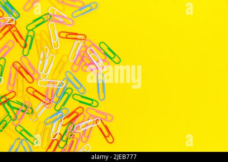 Colored paper clips on a yellow background Stock Photo