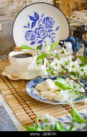 Morning relax, breakfast dishes and decorative elements painted in the style of Gzhel, tea, coffee and white flowers of cherry. Vertical image Stock Photo