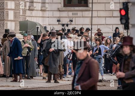 London, UK. 26th June 2022. Filming for BBC series ‘Great Expectations’ continues in Westminster. Extras wearing period dress wait to perform their scenes on King Charles Street. The upcoming period drama, developed by Steven Knight, is based on the novel of the same name by Charles Dickens. A production collaboration between the BBC and FX, the cast was announced in Feb 2022, with Olivia Colman cast as Miss Havisham, and Fionn Whitehead as Pip. Credit: Guy Corbishley/Alamy Live News Stock Photo