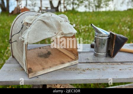 Bee smoker on the top of a bee hive on a summer morning smoking. A beekeeping basic equipment. Beekeeping concept Stock Photo