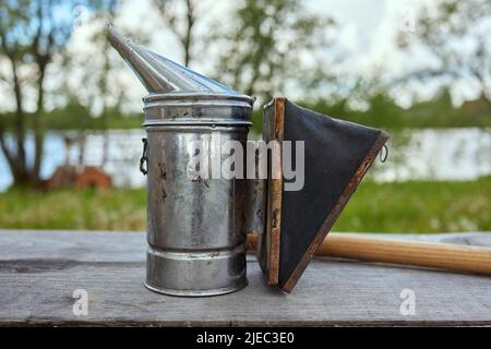 Bee smoker on the top of a bee hive on a summer morning smoking. A beekeeping basic equipment. Beekeeping concept Stock Photo