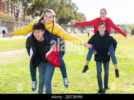Happy teenage boys piggybacking girls Stock Photo