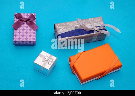 Isolated packed colorful festive gift boxes with bows and silver glitter ribbon on blue background Stock Photo