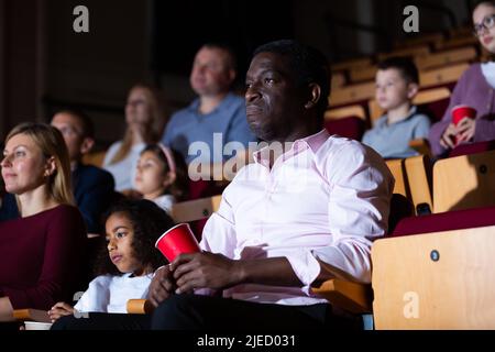 international parents with children sitting at movie in cinema Stock Photo