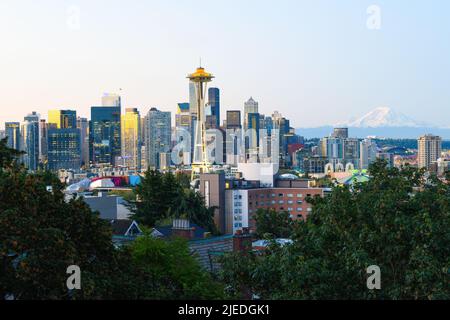 Seattle, WA, USA - June 25, 2022; Early morning sunlight illuminates the skyline of the Seattle cityscape at sunrise with a distant Mount Rainier Stock Photo