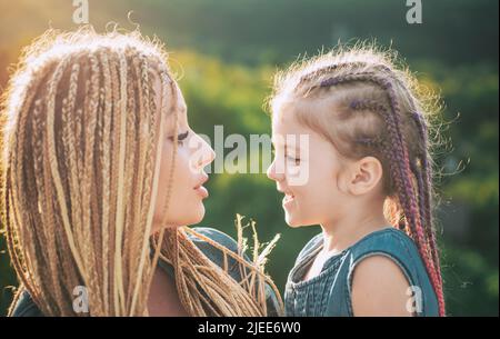 Mother and child girl playing and hugging. Braiding hair. Nice child girl with plaits. Hair in trendy weave plait. Stock Photo