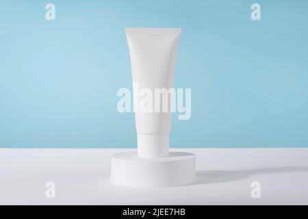 Cosmetic luxury cream tube bottle mockup on blue background on pedestal podium. Unbranded lotion beauty product packaging. Product presentation Stock Photo