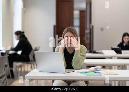 Sleepy tired mature female student feeling exhausted after studying for long hours in library Stock Photo