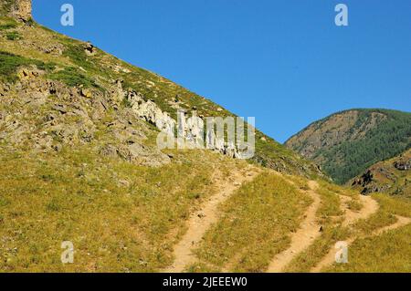 Several paths going along the slope of a high hill to the stone formations on its top. Stone mushrooms, Altai, Siberia, Russia. Stock Photo