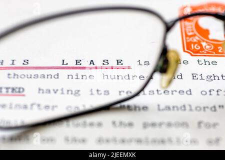 Close up of a lease for a property shown with eye glasses. A legal document for long term rental or ownership of a business premise or home. Stock Photo