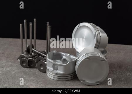 Set of new car pistons and valves on concrete gray background, car repair parts. Stock Photo