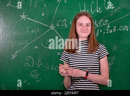 Student girl standing near clean blackboard in the classroom Stock Photo