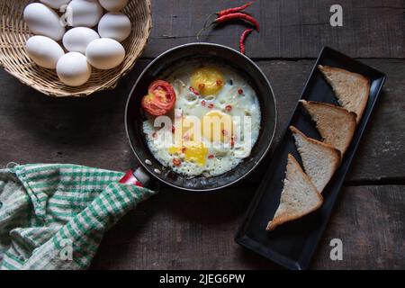 Breakfast item fried eggs in a frying pan on a background. Top view, selective focus. Stock Photo