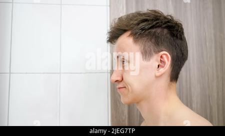 Sleepy man stands in bathroom rubbing eyes. Stock Photo
